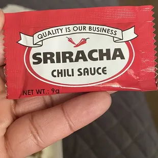 a hand holding a package of chili sauce