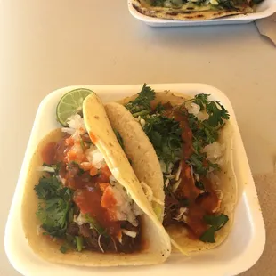 Two barbacoa tacos with toppings.