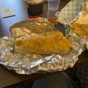 two burritos wrapped in aluminum foil
