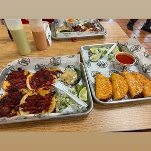 two trays of tacos and a side dish