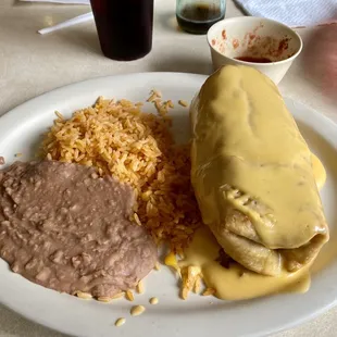 This is a chicken chimichanga served with rice and refried beans.