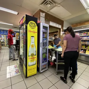 Food preparation outside the kitchen area, with customers walking behind to grab items from the refrigerator
