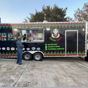 a woman standing in front of a food truck