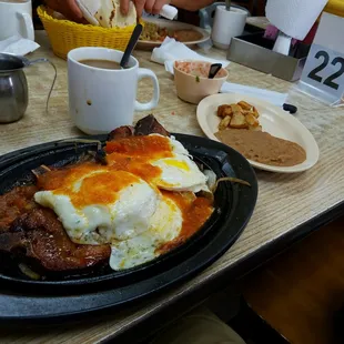 The desayuno a la parrilla de chuletas de puerco. Skillet pork chops with Mexican style eggs.