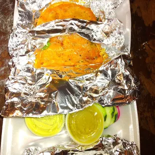 three tacos wrapped in aluminum foil