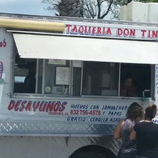 two people standing in front of a food truck