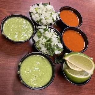 Guacamole salsa, hot salsa, limes, and onions and cilantro
