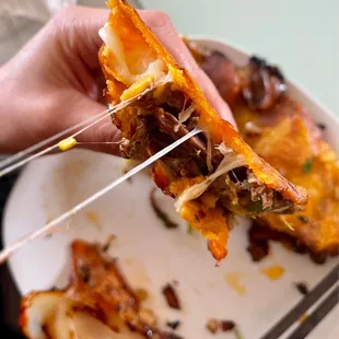 a hand holding a piece of mexican food