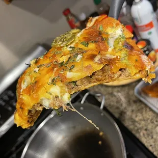a hand holding a piece of pizza