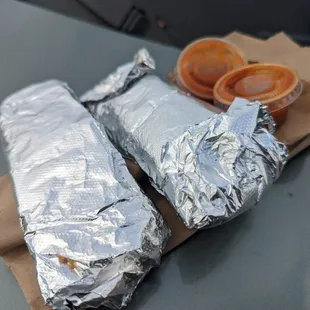 two burritos wrapped in aluminum foil