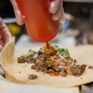 a person adding sauce on a tortilla