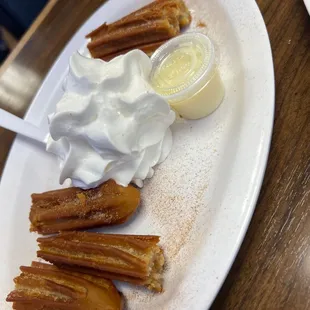 a plate of churros and whipped cream