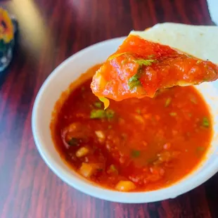 a tortilla being dipped with salsa