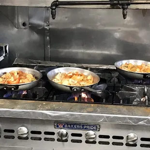 three pans of food cooking on a stove