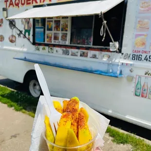 a person holding a cup of food in front of a food truck
