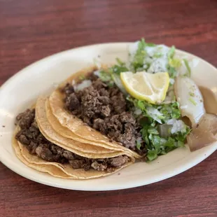 a plate of tacos with a lemon wedge