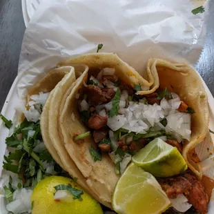 Two takeout tacos:  asada (left), and pastor (right).