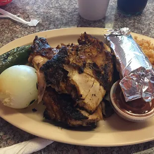 Half a chicken with Mexican rice, whole grilled onion, grilled jalapeño pepper with corn tortillas.