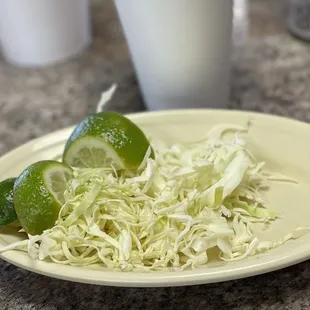 a plate of shredded cabbage and limes