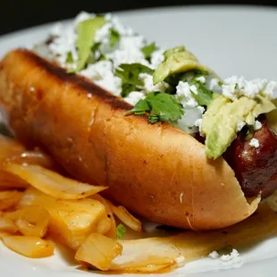 a hot dog with onions and avocado
