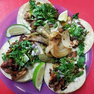 a plate of tacos with meat, onions, and cilantro