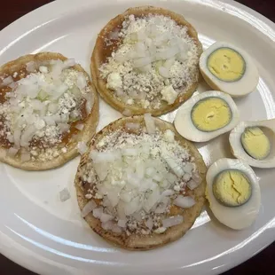 Picaditas(3) Corn tortillas with pinched sides cooked in a hot griddle and topped with green or red salsa, onions and cheese