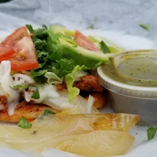 a taco sandwich with lettuce, tomatoes, onions, and avocado