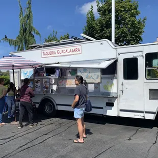 a group of people standing around a food truck