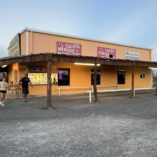 two people standing outside of a restaurant