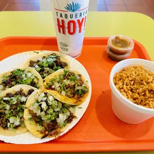 a plate of tacos, rice and a drink