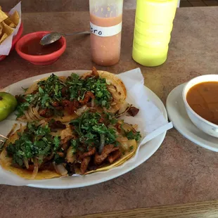 Tacos al pastor with charro beans. Green sauce and habanero salsa in the bottles.