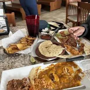 enchiladas with rice and beans along with carne guisada featuring chunks of lean beef steak simmered with chunks of lean beef steak