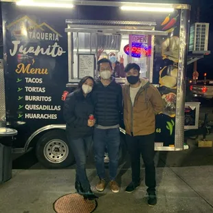 three people standing in front of a food truck