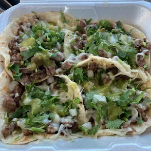 Carne Asada Tacos with cheese, cilantro, onions, and salsa verde.