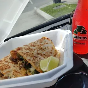 a person holding a drink and a plate of quesadillas