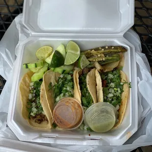 Carne asada, lengua, and barbacoa tacos with green and red salsa