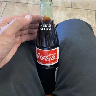 a person holding a bottle of coke