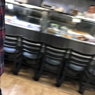 a blurry image of a man walking past a restaurant counter