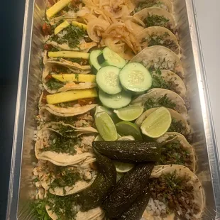 a variety of tacos in a foil container