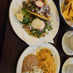 Carne asada and carnitas tacos with rice and beans.