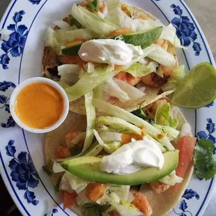 Shrimp tacos made with hand made tortillas, shrimp, lettuce, avocados, tomatoes, onion and cilantro.