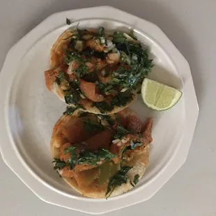 2 Chicharron tacos. Note the blending of the very spicy red sauce they are cooked in and the dash of green sauce to complement. Quite good!