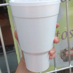 a hand holding a plastic cup with a straw