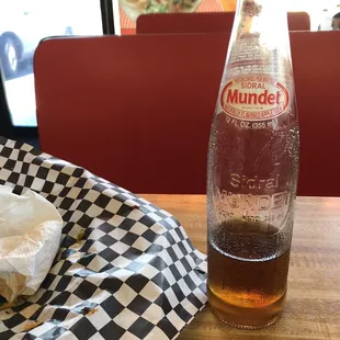 a bottle of mundent soda and a napkin on a table