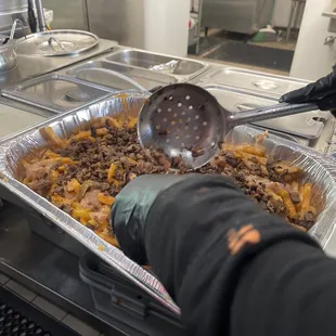 a person scooping food out of a pan