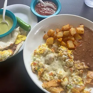 Migas, papas, y frijoles refritos.  To the left is an egg and bean taco, salsa roja, and a green doña-style salsa.