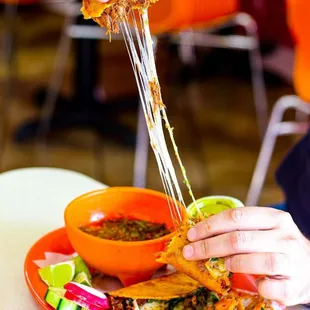a person dipping sauce onto a tortilla