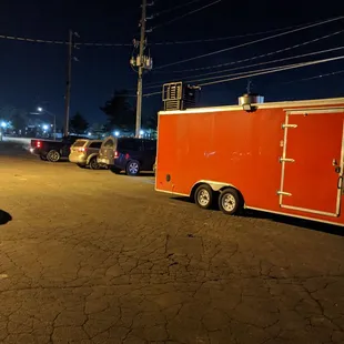 The backside of the taco truck and there were two lines of cars parked in the parking lot.