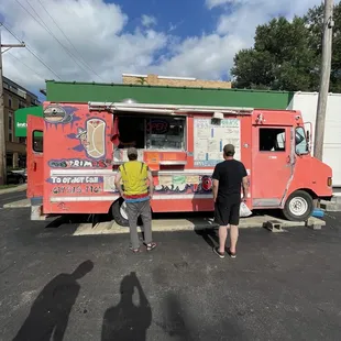 two people standing in front of a food truck