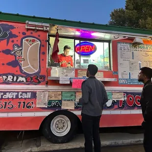 two people standing in front of a food truck
